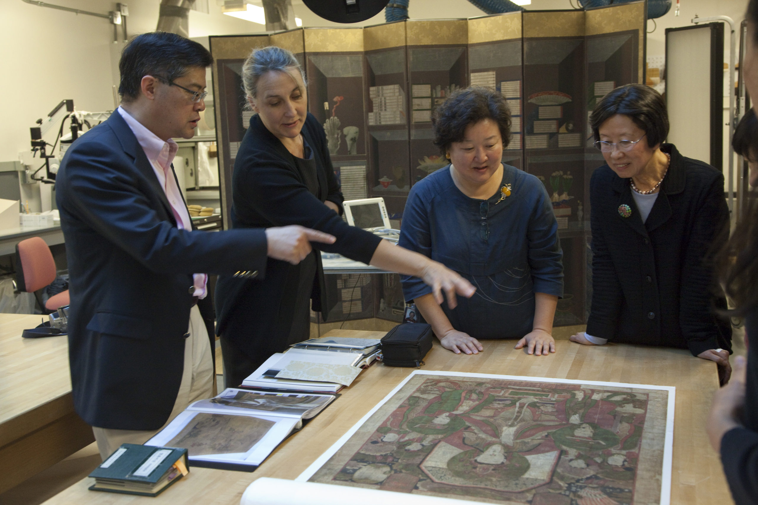 A group of conservators and curators study a painting.