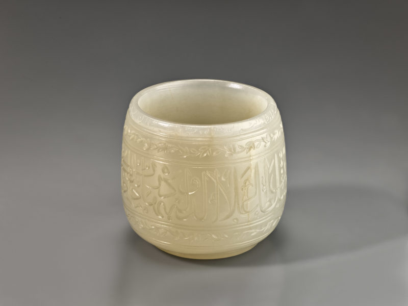 Detailed view from above of a white jade cup with calligraphic inscriptions around the body