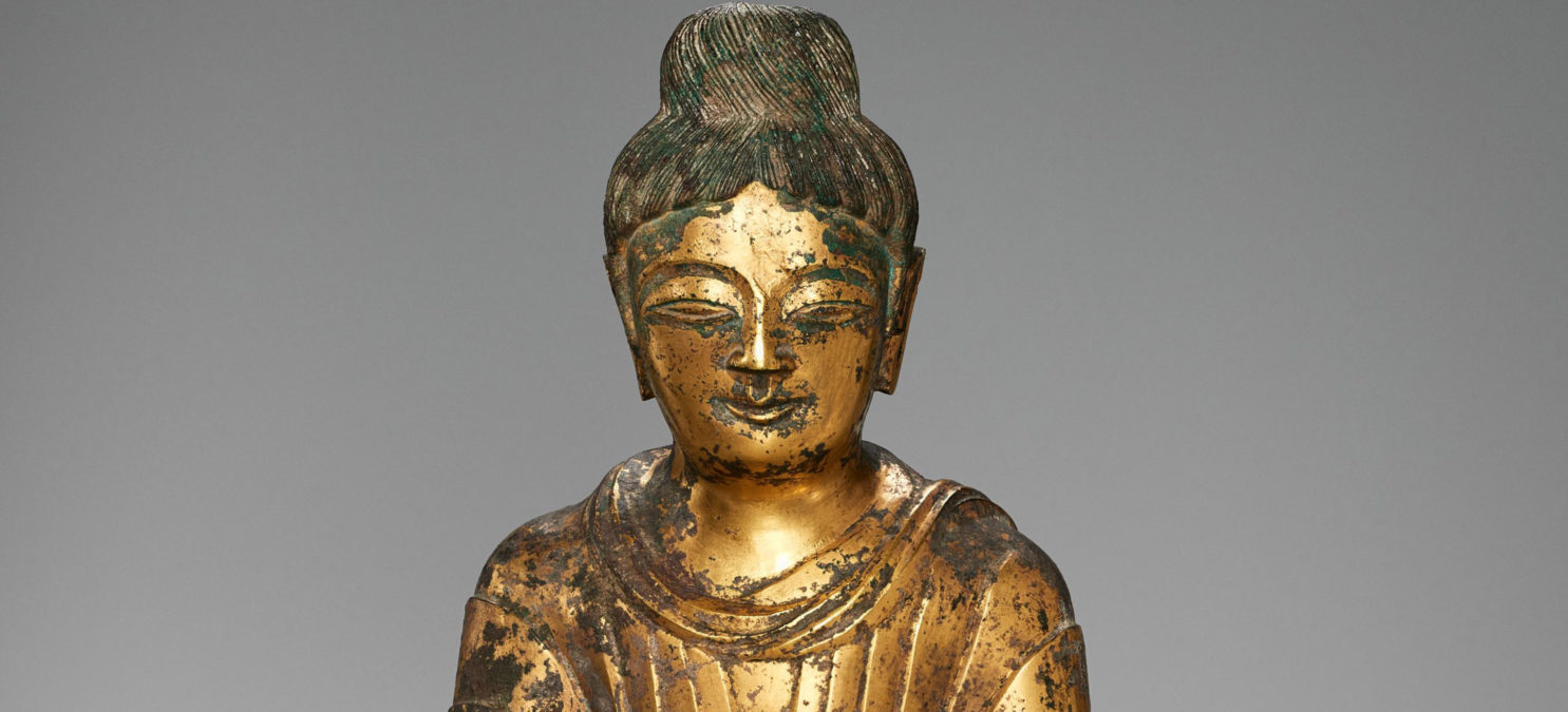 Face and shoulders of a golden Buddha statue.