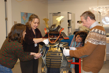 A group of conservators adjust the many parts of the Japanese suit of armor.